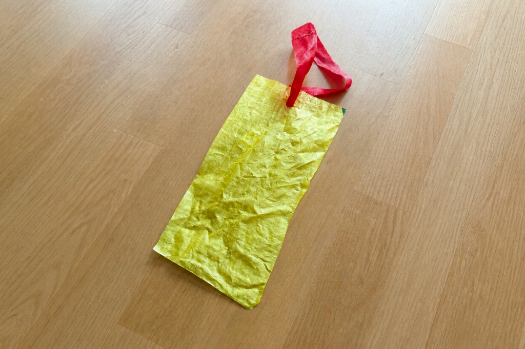 Exhibition tag constructed of raw canopy remnants hung on a loop cut from the canopy itself.